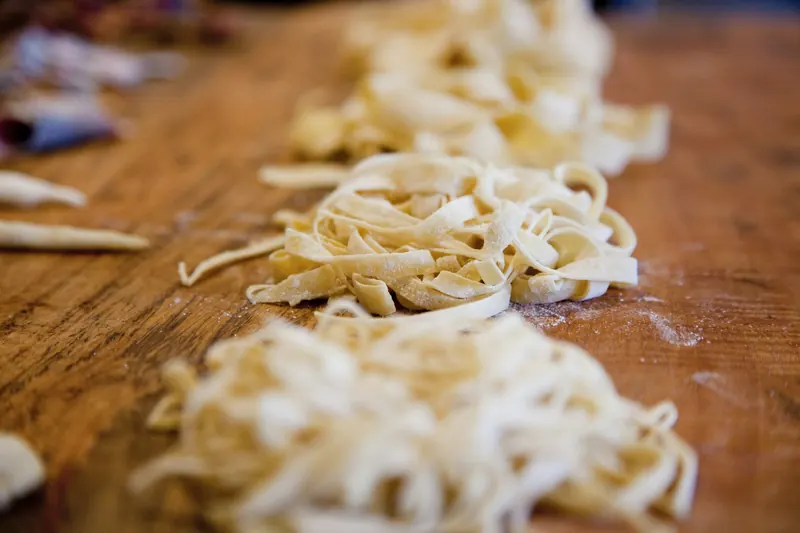 Nidi di tagliatelle fresche sul tagliere di legno